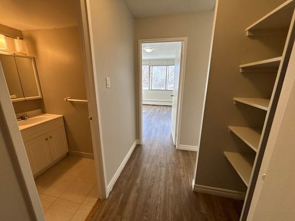 A hallway with a wooden floor and white walls.
