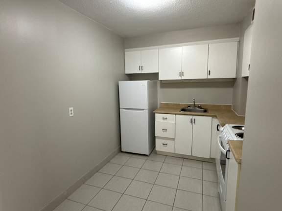 A kitchen with white appliances and cabinets.