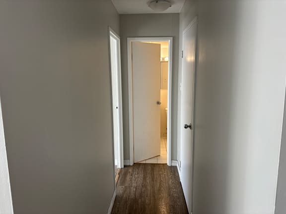 A hallway with a wooden floor and white walls.