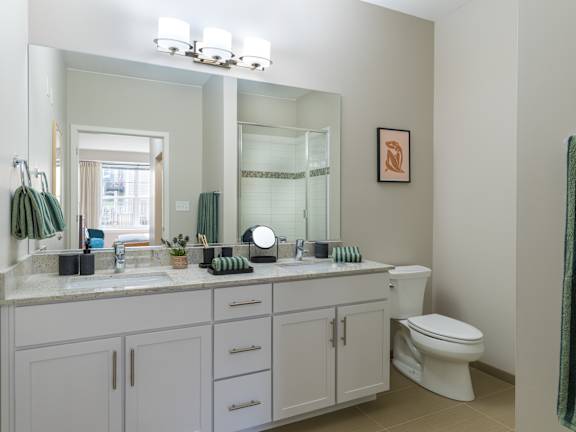 A bathroom with a white toilet, sink, and cabinets.