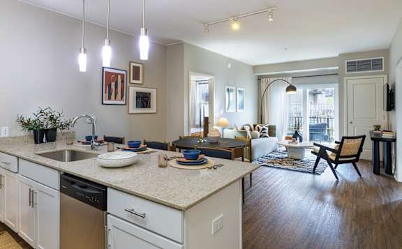 A kitchen with a sink, counter, and chairs.