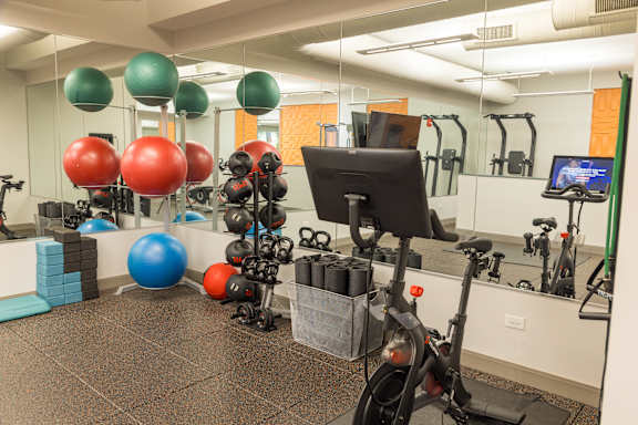 A gym with a variety of equipment including a stationary bike, a treadmill, and a rowing machine.