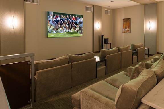 A room with a row of couches and a television showing a football game.