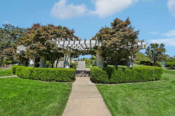 A white arched structure with trees growing on it.