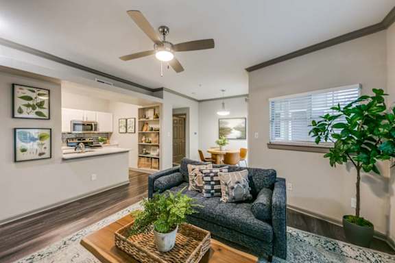 A living room with a blue couch and a ceiling fan.