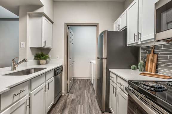 A modern kitchen with white cabinets and stainless steel appliances.