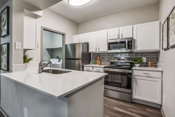 A modern kitchen with stainless steel appliances and white cabinets.