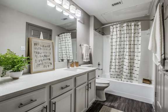 A bathroom with a toilet, sink, and a mirror.
