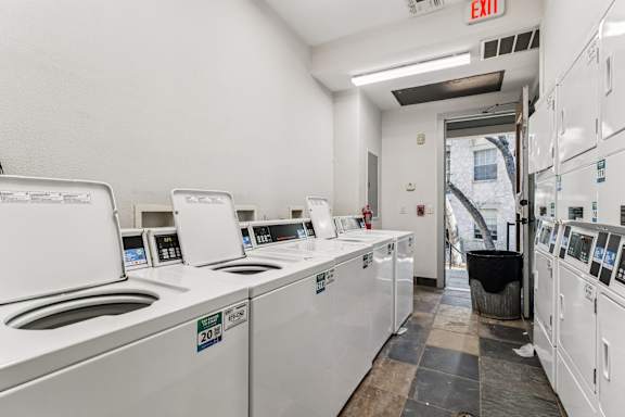 A laundromat with a row of washers and dryers.