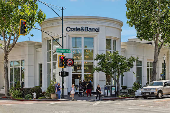 A Crate & Barrel store is shown with people walking by and a car parked in front.