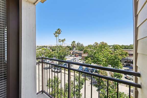 A balcony view of a parking lot and trees.