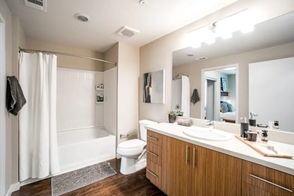 A bathroom with a white toilet, sink, and shower.