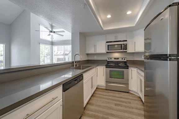 A modern kitchen with stainless steel appliances and wooden flooring.