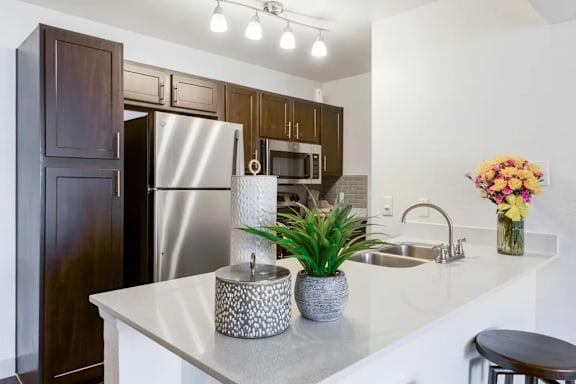 A kitchen with a white counter top and a stainless steel refrigerator.