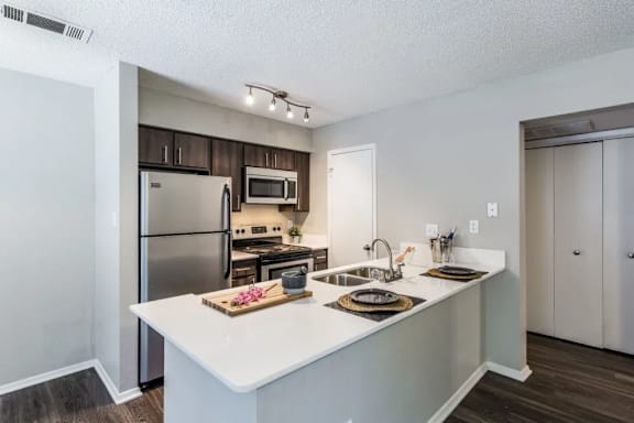 A modern kitchen with a white countertop and stainless steel appliances.