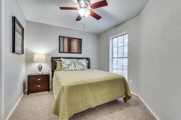 A bedroom with a bed, nightstand, and a ceiling fan.