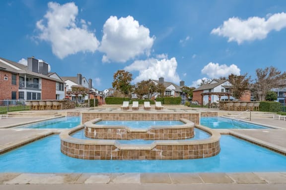 A large outdoor swimming pool with a hot tub in the middle.
