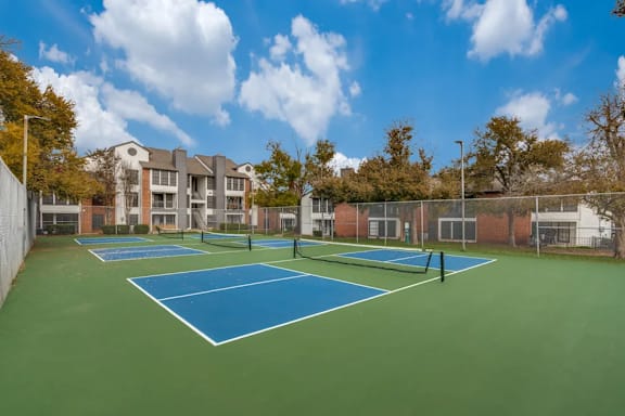 A tennis court surrounded by a fence and trees.