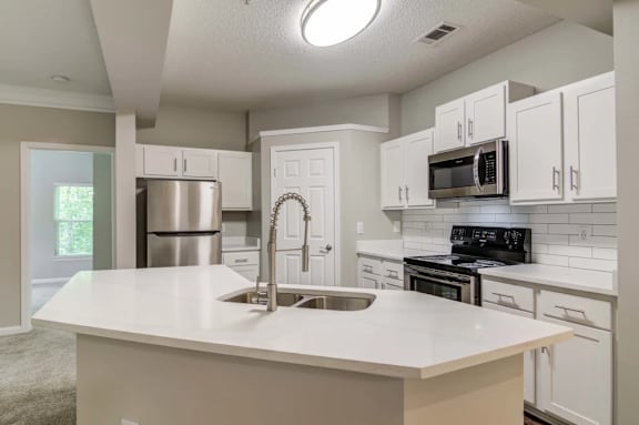 A kitchen with a white countertop and stainless steel appliances.