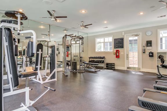 A spacious gym with a variety of equipment and a fire extinguisher on the wall.
