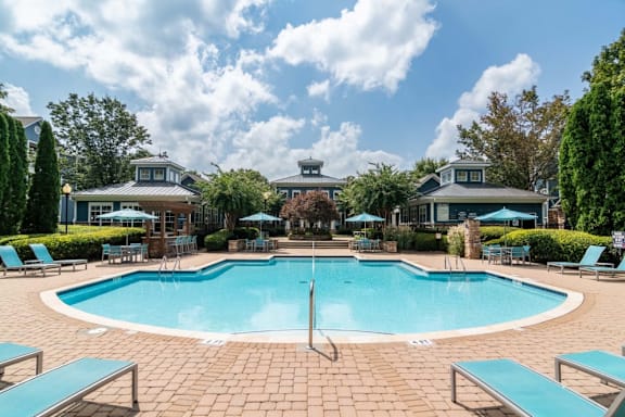 A large swimming pool surrounded by lounge chairs and umbrellas.