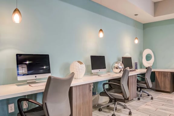 A modern office with two computers and four chairs.