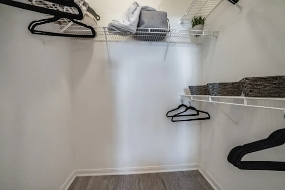 A white closet with clothes hanging on hangers.