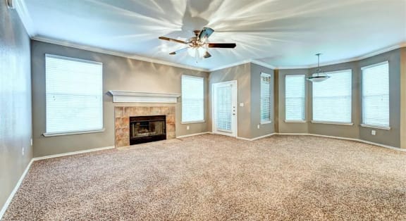 A spacious room with a fireplace and a ceiling fan.