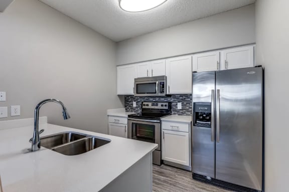 A kitchen with a stainless steel refrigerator, microwave, oven, and sink.
