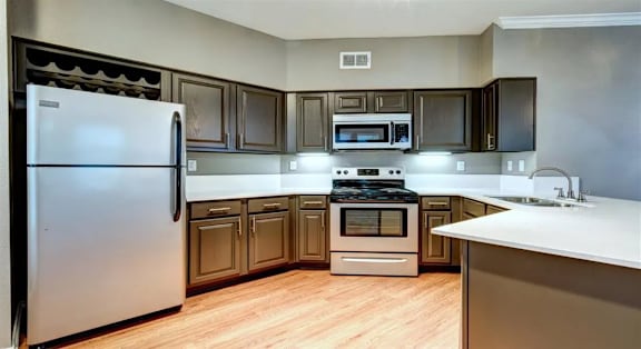 A kitchen with a stainless steel refrigerator and wooden cabinets.