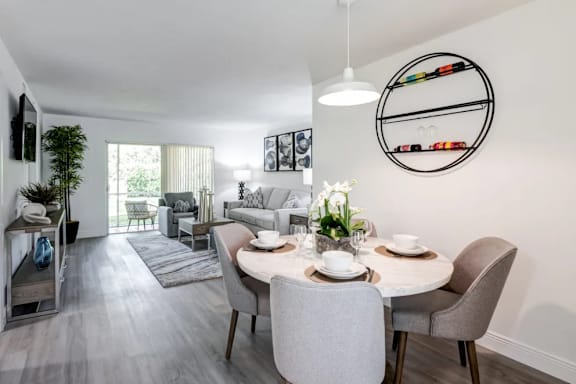 A modern dining room with a white table and grey chairs.