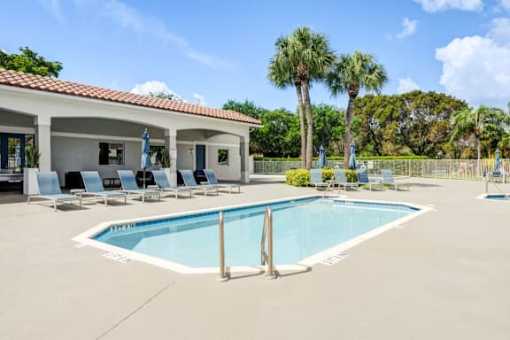 A pool with a white fence and a building behind it.