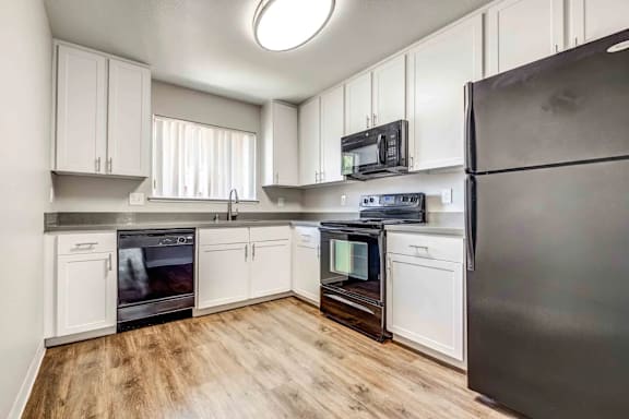 A kitchen with white cabinets and black appliances.