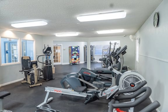 A gym with a variety of equipment including a treadmill, stationary bike, and weight bench.