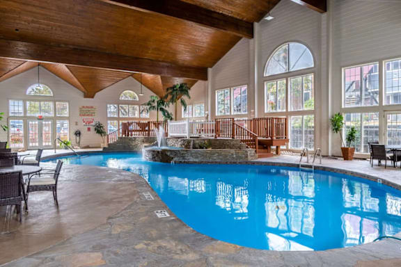 A large indoor swimming pool with a stone edge and a waterfall feature.
