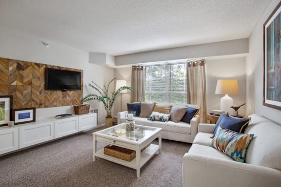 A living room with a white couch, a coffee table, and a wooden wall panel.