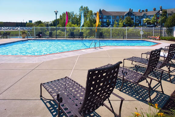 A pool surrounded by chairs and flags.