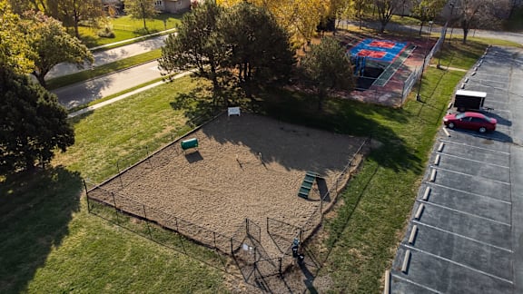 A playground with a red car parked in the parking lot.