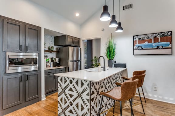 A kitchen with a white island and brown chairs.