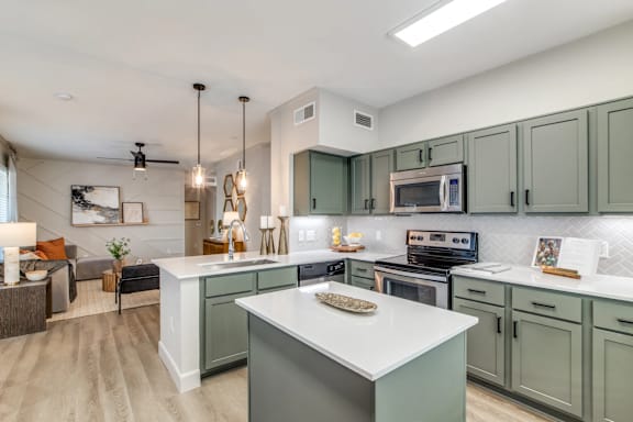 A modern kitchen with a white island and green cabinets.