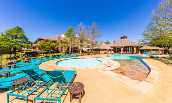 A large outdoor swimming pool surrounded by blue lounge chairs.
