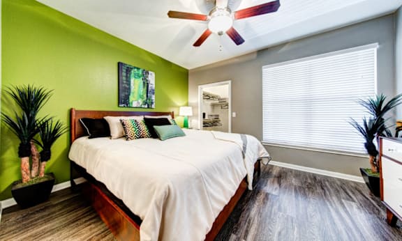 A bedroom with a bed, a ceiling fan, and a mirror.