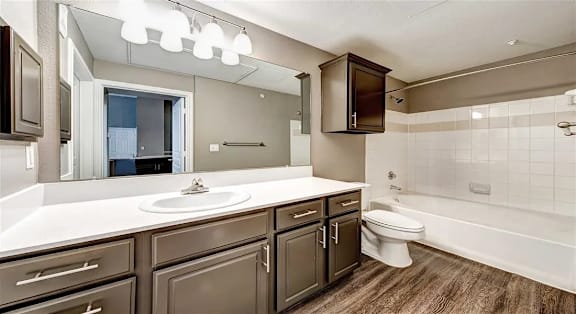 A bathroom with a white countertop and brown cabinets.