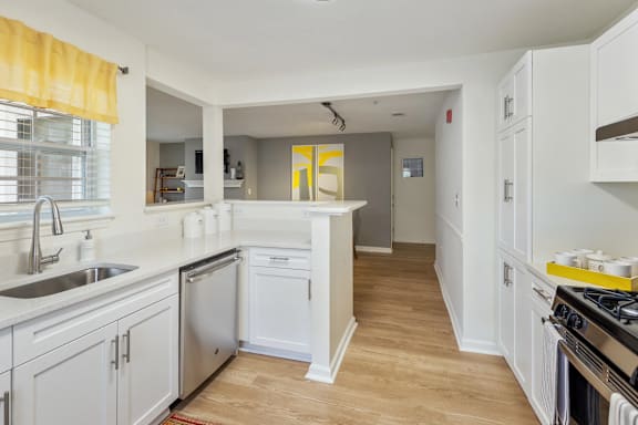 A kitchen with white cabinets and a wooden floor.
