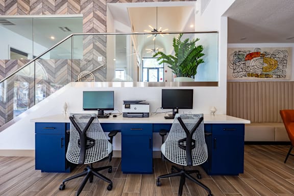 Two chairs and a desk with a laptop and monitor on it.