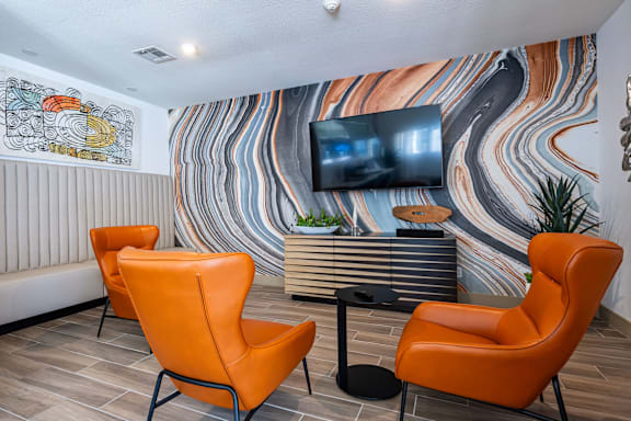 A room with orange chairs and a colorful wallpaper.