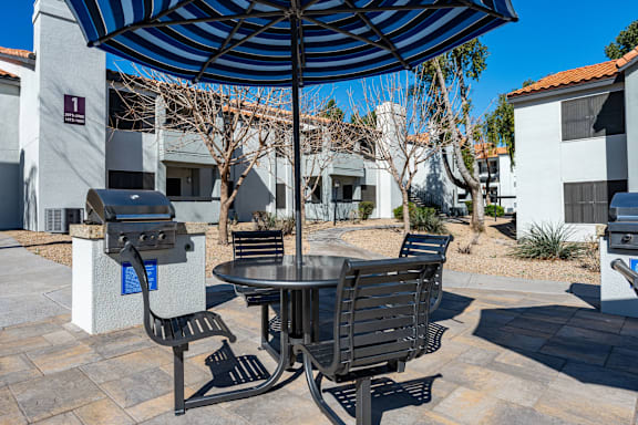 A patio with a table and chairs under an umbrella.