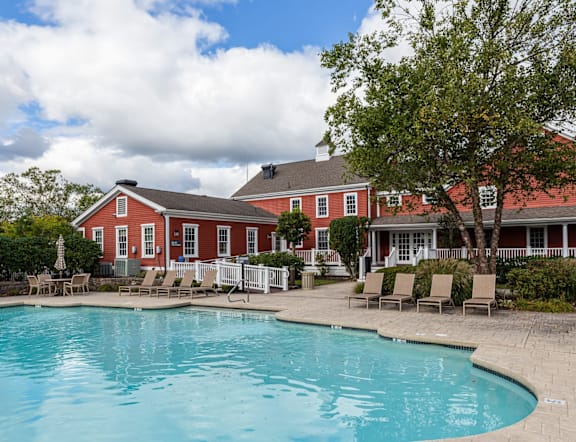 A red house with a pool in front.