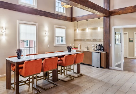 A kitchen with a long table and orange chairs.