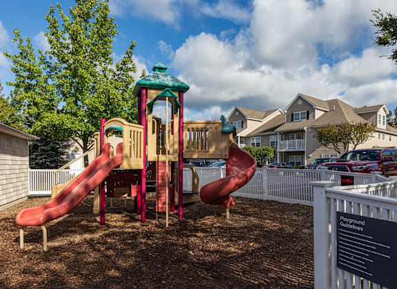 A playground with a red slide and a green roofed structure.